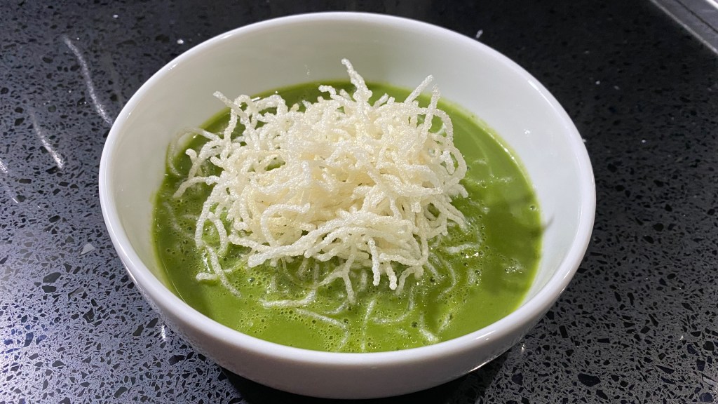 White crisping noodles on green thai broth in a bowl