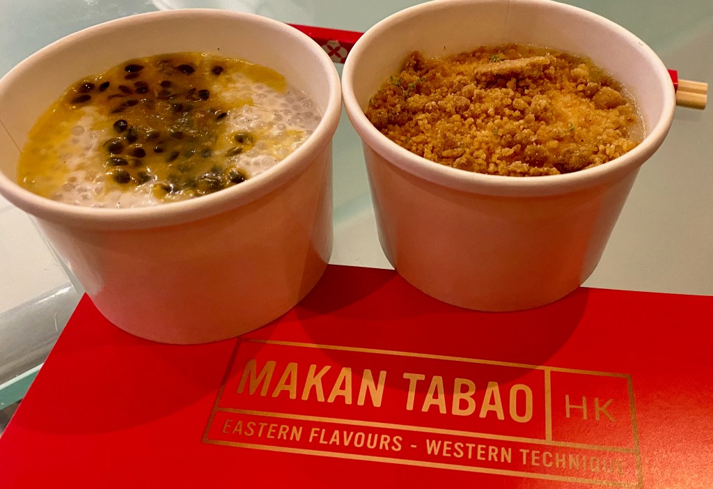 Two small round takeaway containers one with white sago pudding topped with passion fruit the other lime cheesecake topped with ginger crumb. Pots on Makan Tabao gold logo on red.